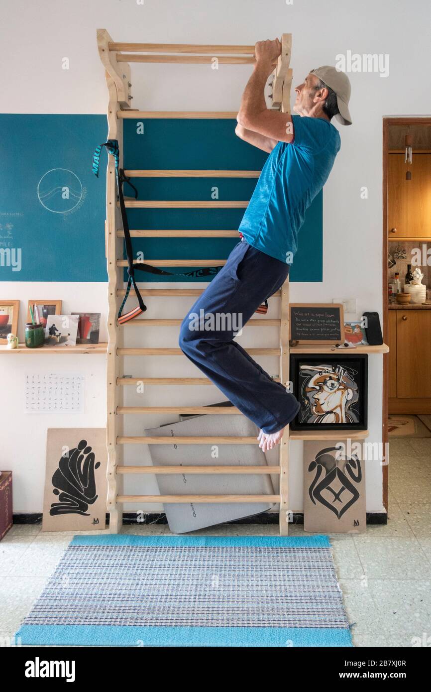 61 ans, homme, et l'exercice à la maison sur des barres de mur en petit appartement. Banque D'Images