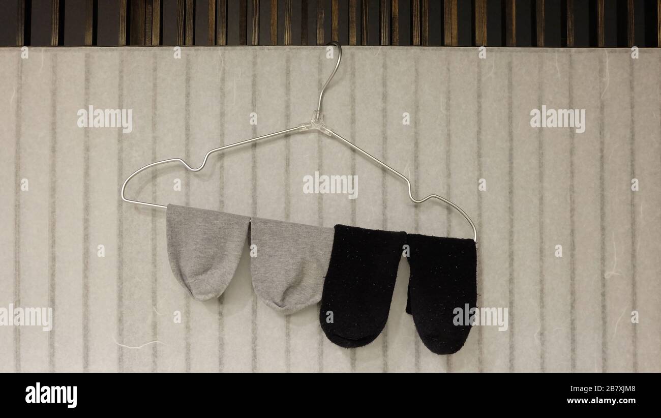 2 paires de chaussettes en gris et en noir respectivement, pendues sur un cintre. Banque D'Images