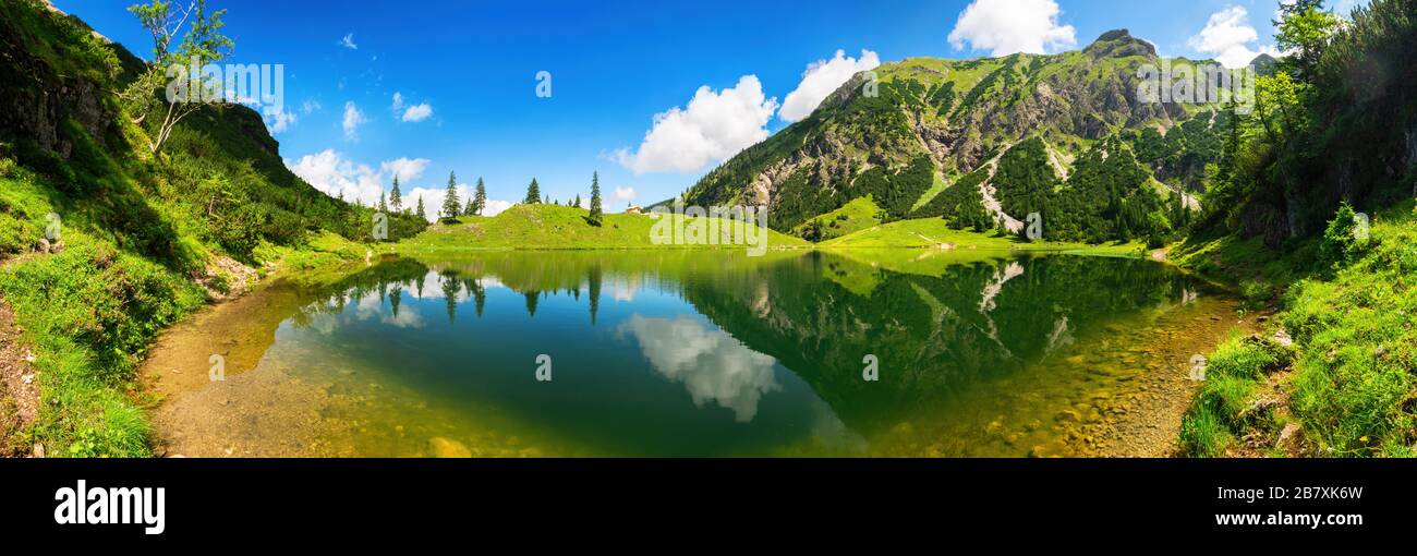Magnifique lac entouré de montagnes, avec un ciel bleu profond ensoleillé et le paysage étonnant reflété dans l'eau claire Banque D'Images
