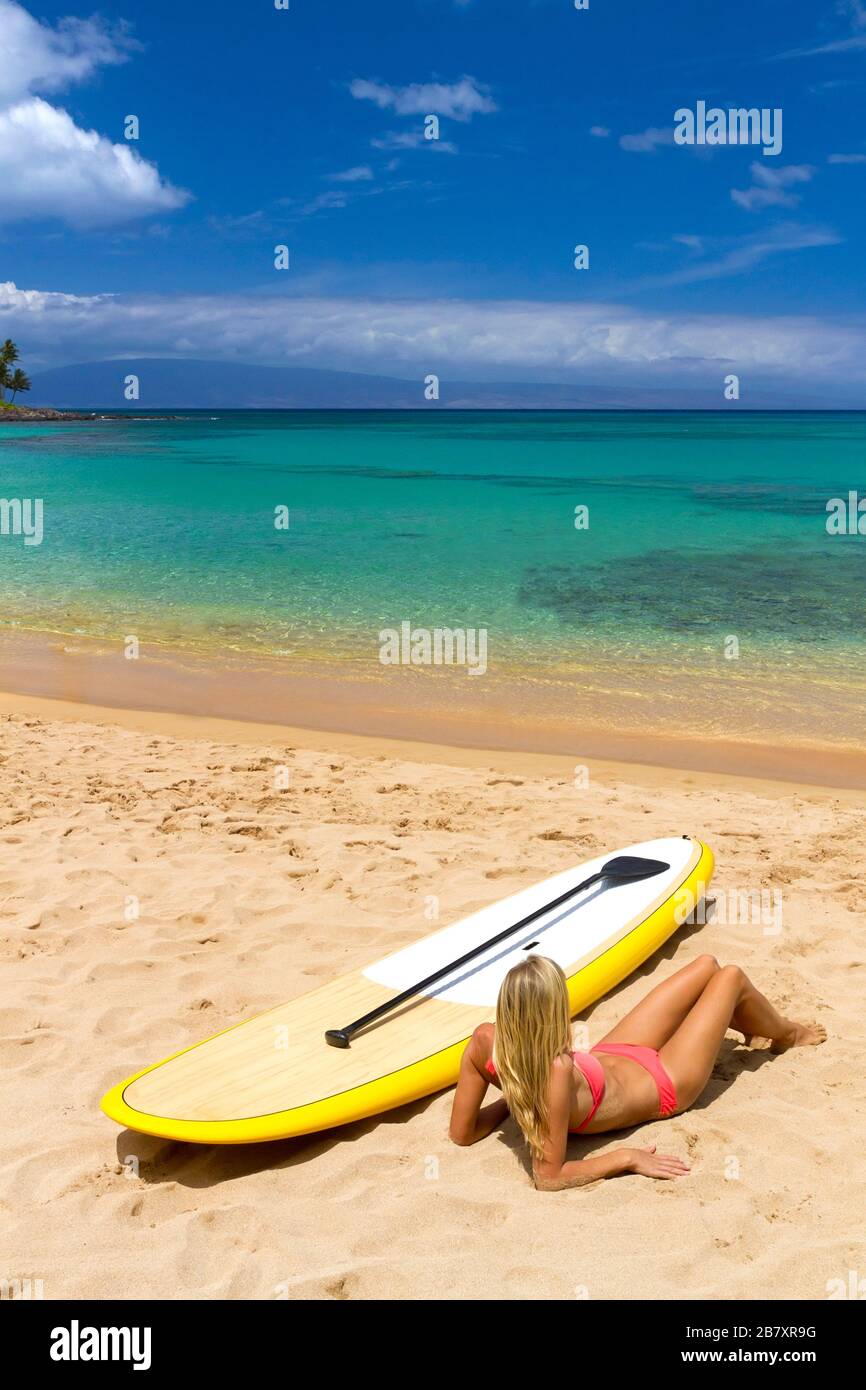 Femme se détend sur la plage de Napili, Maui, Hawaï, avec stand up paddleboard. Banque D'Images