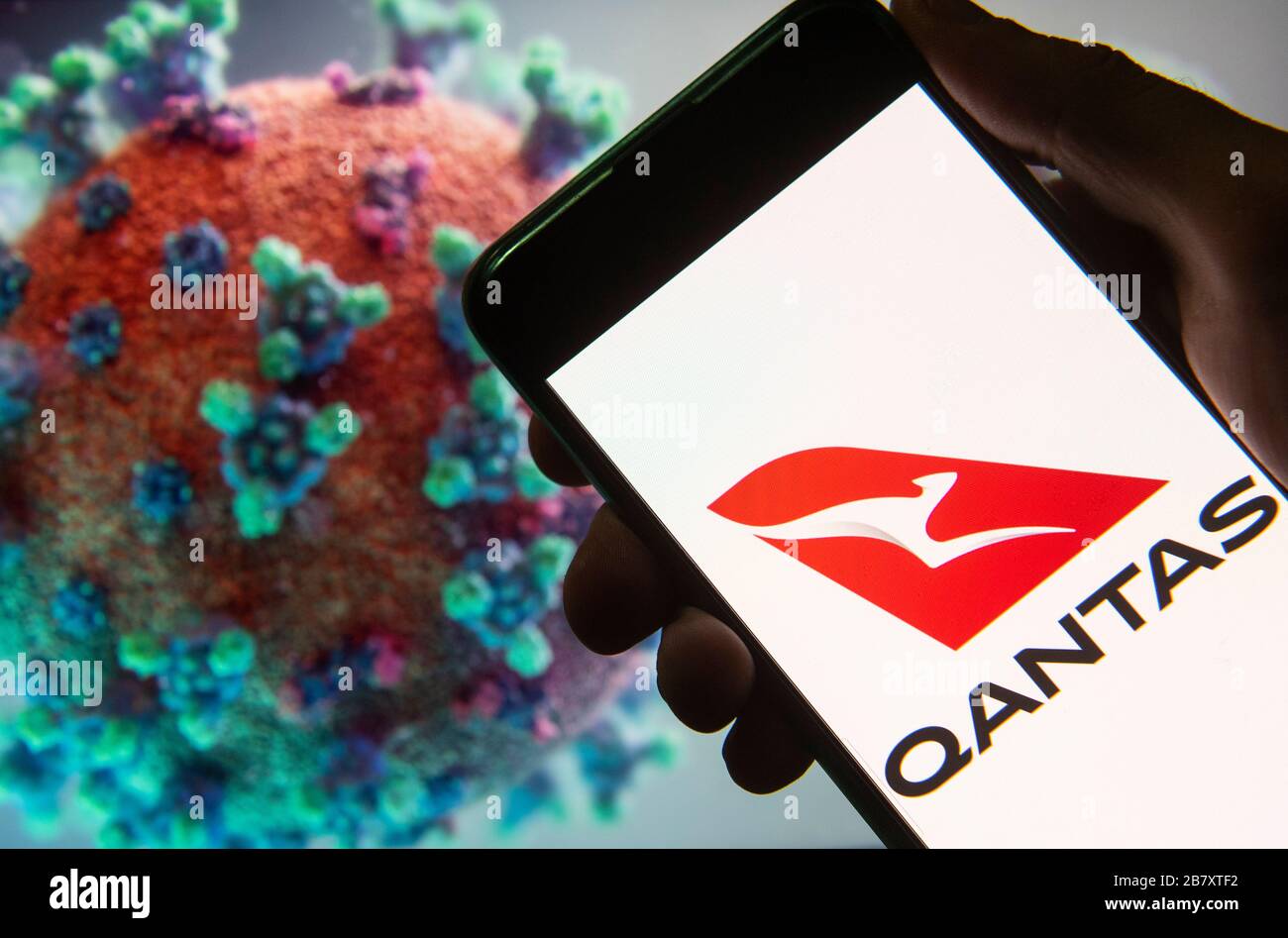 Dans cette photo illustration, le transporteur de retard de l'Australie et son plus grand logo de compagnie aérienne Qantas Airlines, visibles sur un smartphone avec un modèle d'ordinateur du coronavirus COVID-19 en arrière-plan. Banque D'Images