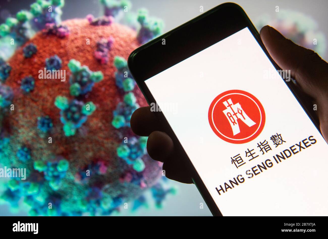 Dans cette illustration photo, le logo Hang Seng Indexes est affiché sur un smartphone avec un modèle d'ordinateur du coronavirus COVID-19 en arrière-plan. Banque D'Images