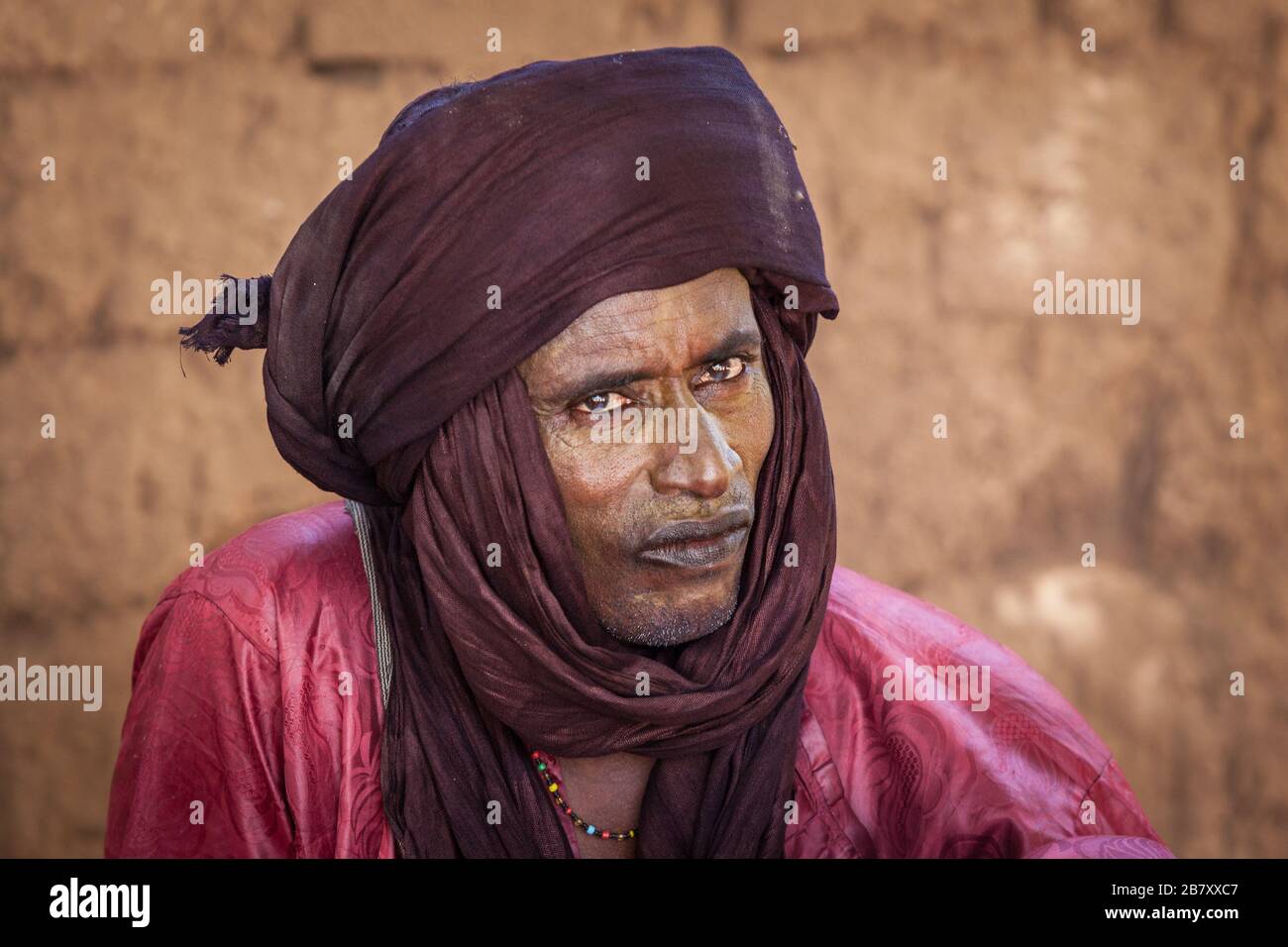 Tuareg nomad vieil homme dans le portrait traditionnel turban gros plan mur d'argile Banque D'Images