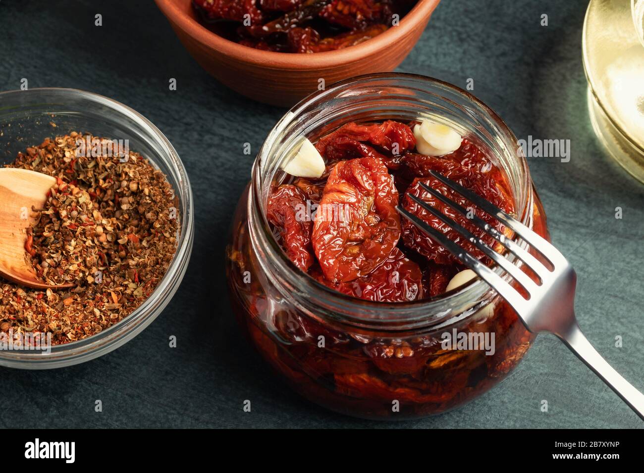 Faire cuire des tomates séchées au soleil dans un pot en verre avec de l'huile d'olive, de l'ail et des épices. Banque D'Images