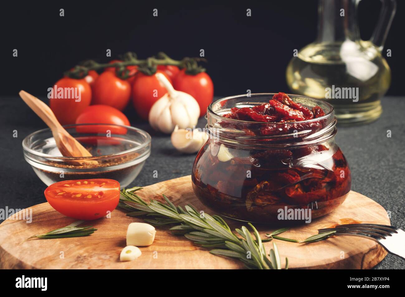Faire cuire des tomates séchées au soleil dans un pot en verre avec de l'huile d'olive, de l'ail et du romarin. Banque D'Images