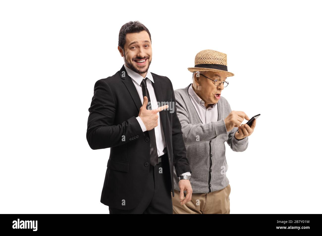 Jeune homme en costume riant et pointant vers un homme âgé avec un téléphone portable isolé sur fond blanc Banque D'Images