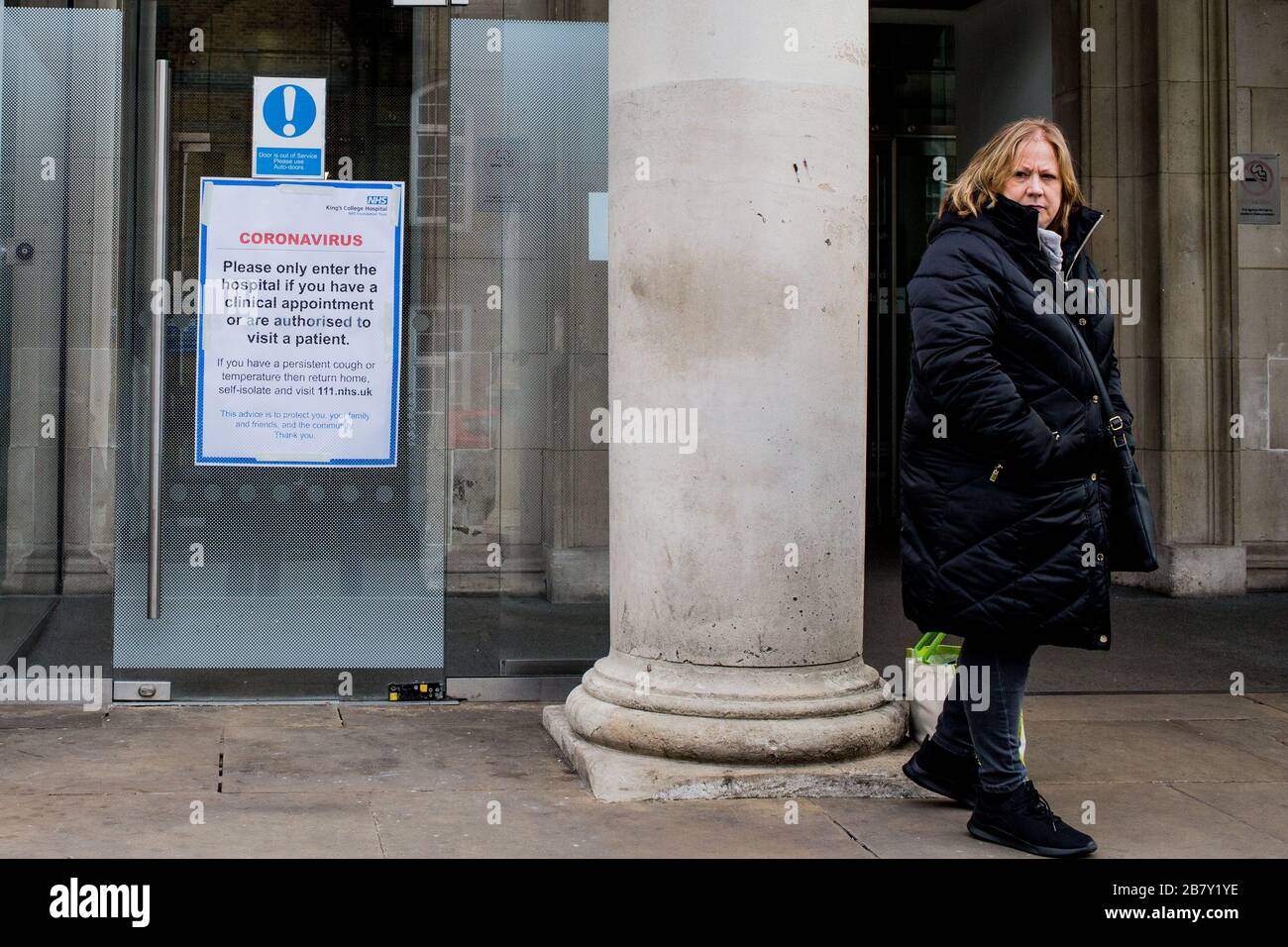 Londres Royaume-Uni 17 mars 2020 UNE femme se tient près d'une affiche NHS Coronavirus à l'entrée de l'hôpital King's College de Denmark Hill, Camberwell. Banque D'Images