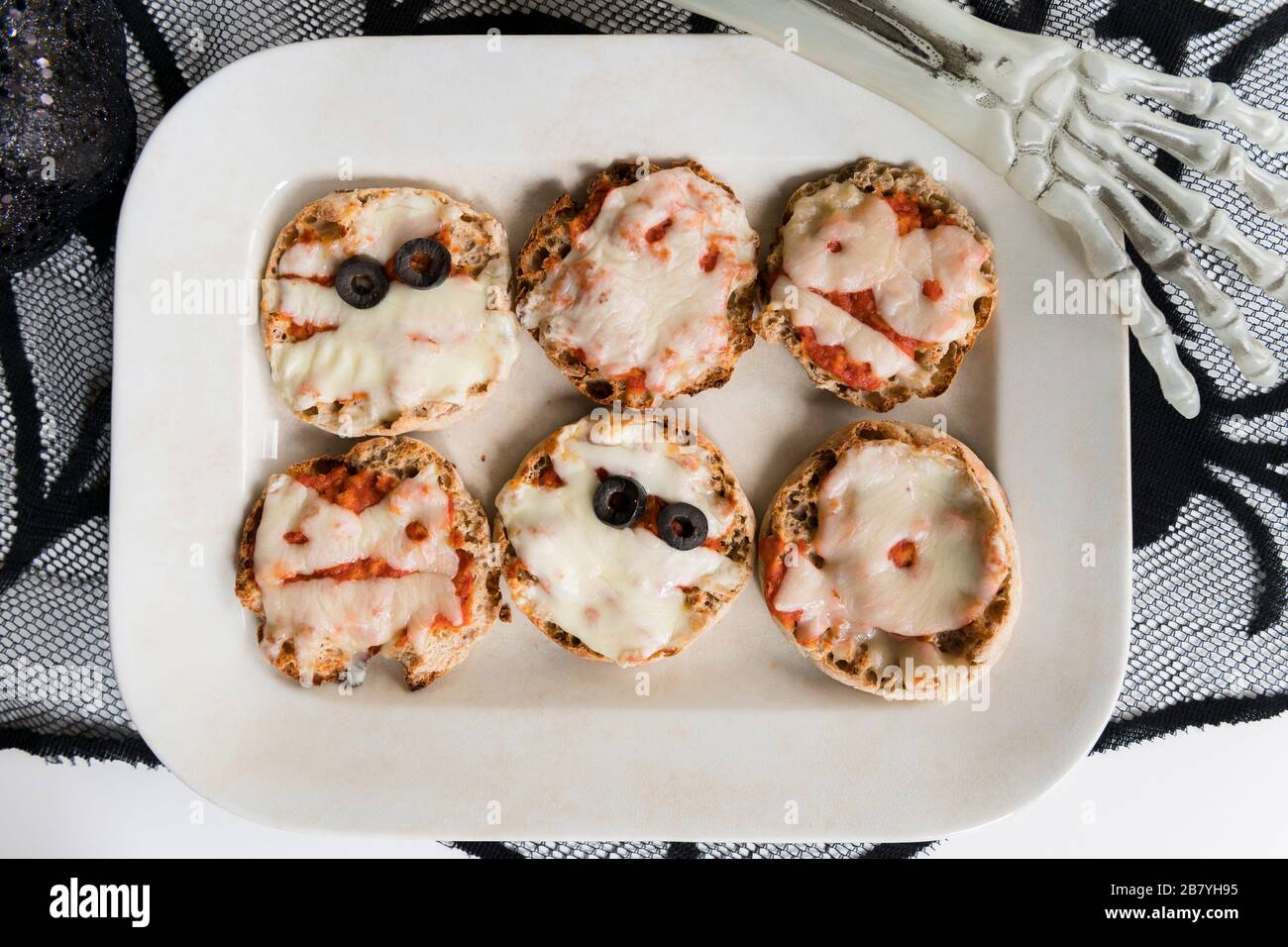 Assiette de mini pizzas et main de squelette d'Halloween Banque D'Images