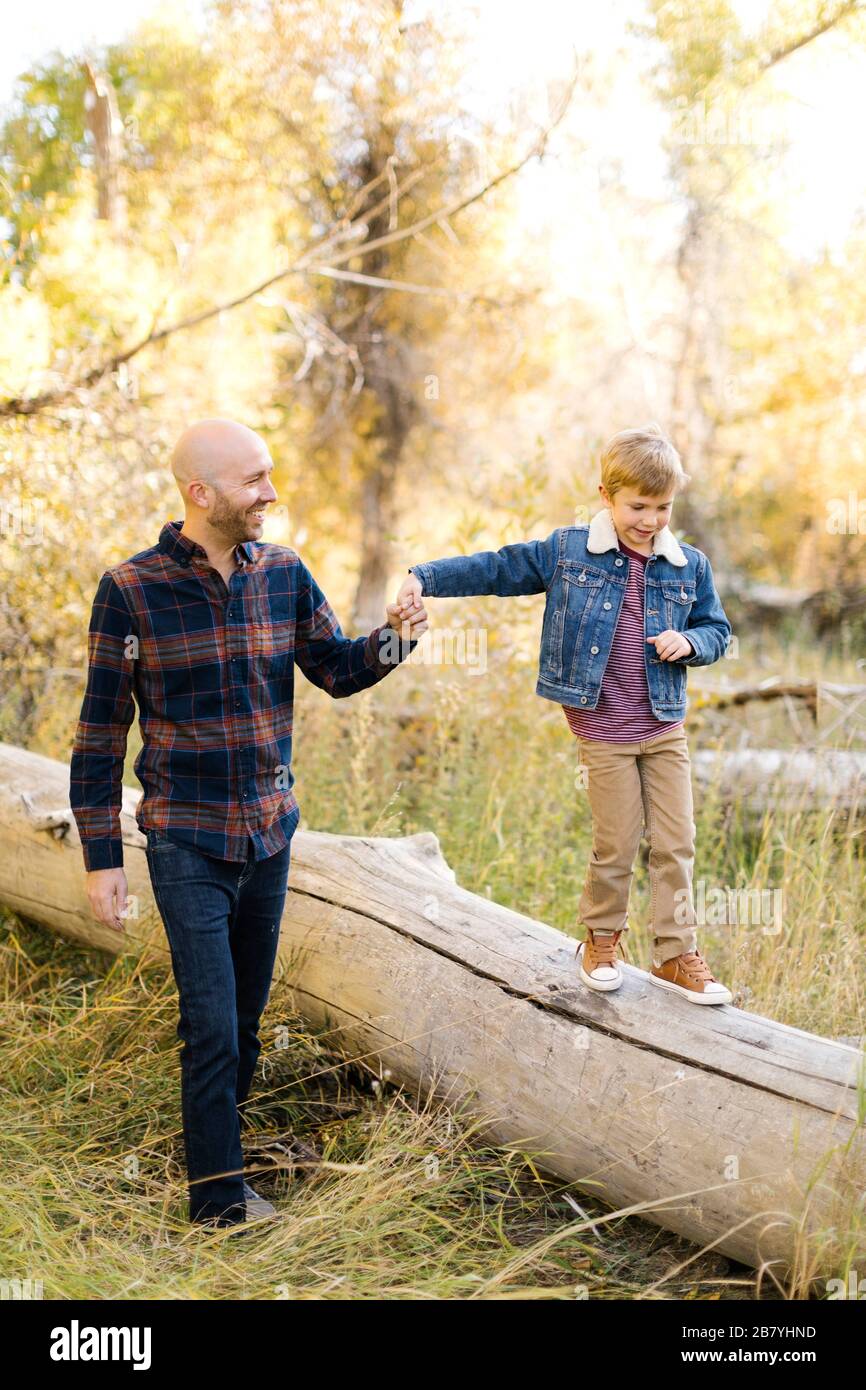 Homme tenant la main de son fils lorsqu'il marche sur l'arbre tombé Banque D'Images