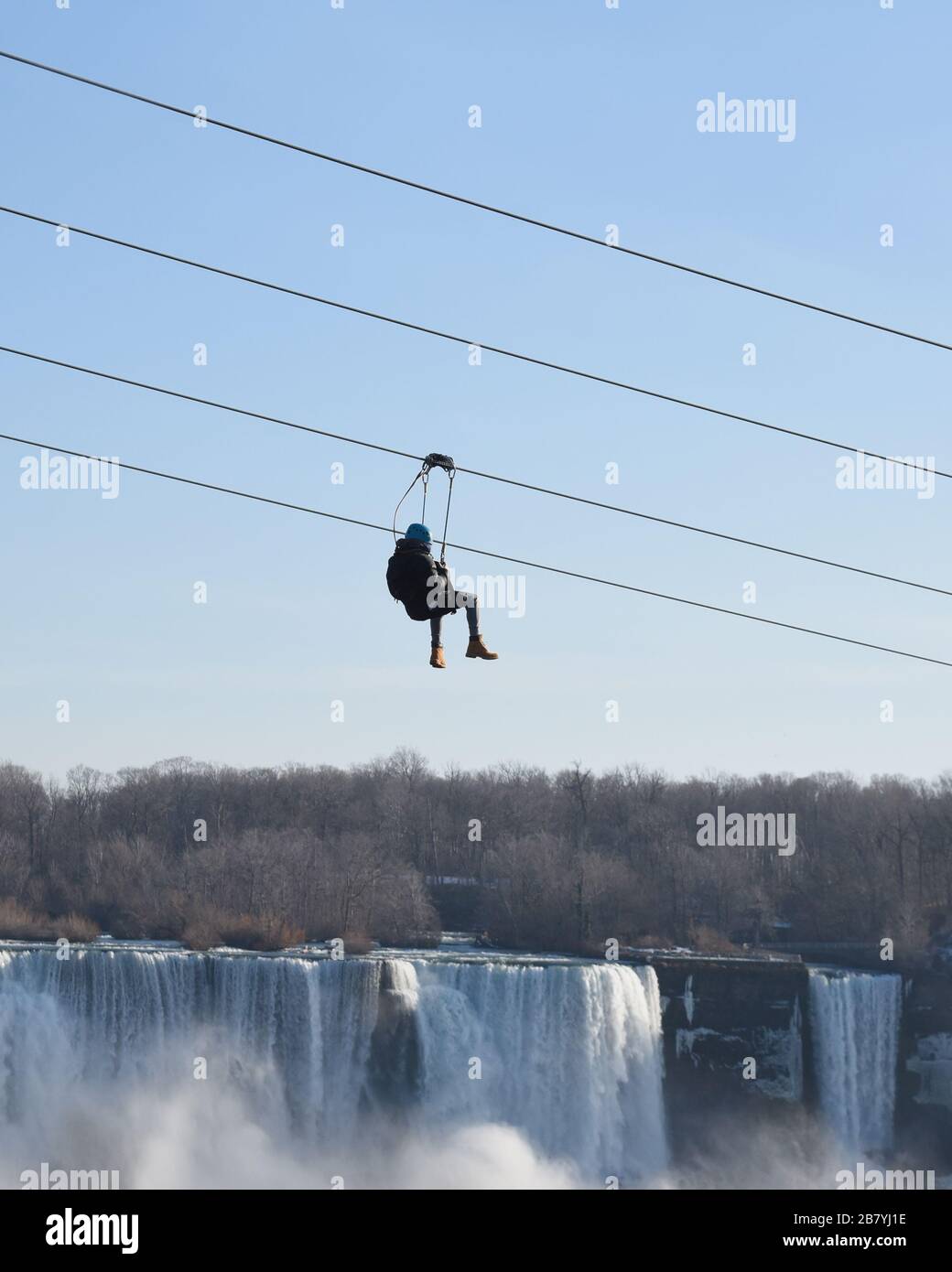 Une personne monte une ligne éclair vers le bas avec la chute d'eau des chutes du Niagara en arrière-plan pour un concept d'activité touristique de vacances. Banque D'Images
