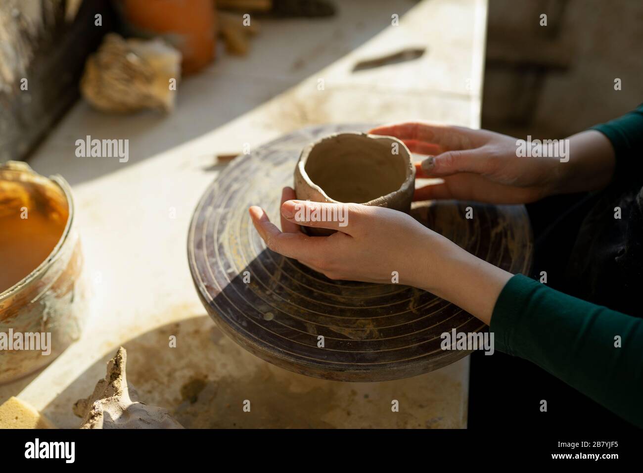 Mains de la femme moulant l'argile sur la roue de potter Banque D'Images