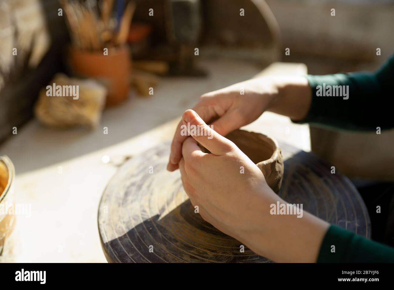 Mains de la femme moulant l'argile sur la roue de potter Banque D'Images