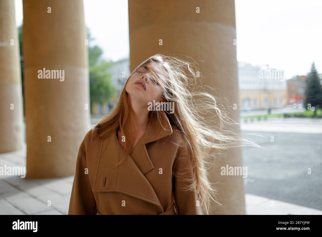Jeune femme avec des cheveux soufflés par le vent par des colonnes Banque D'Images