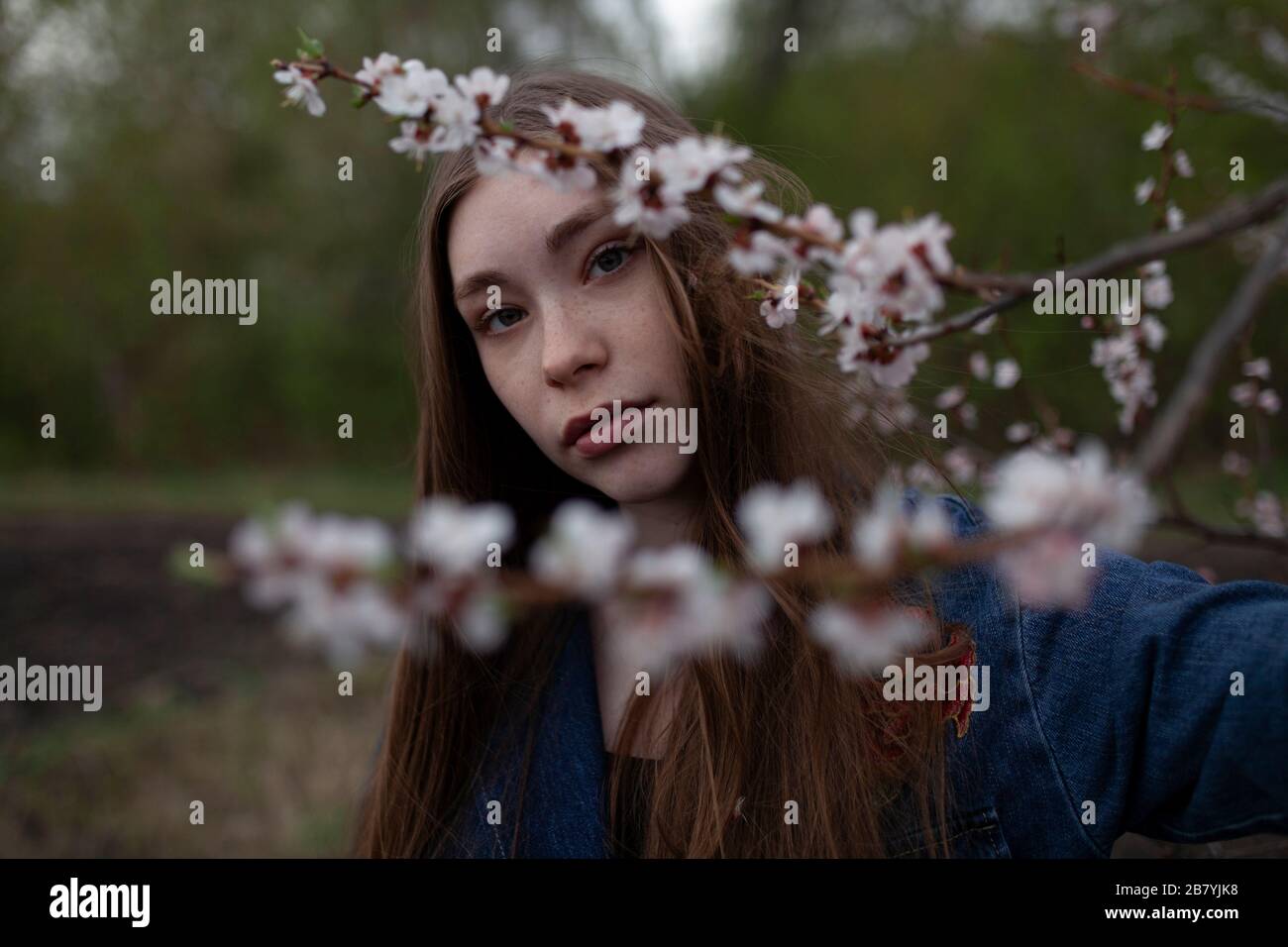 Jeune femme derrière des branches avec des fleurs Banque D'Images