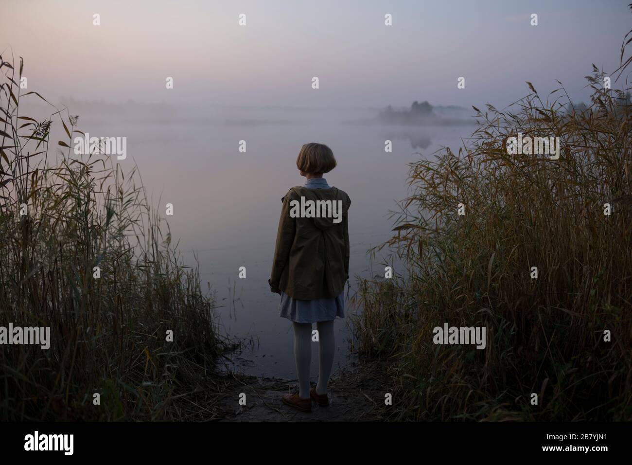 Jeune femme au bord du lac au coucher du soleil Banque D'Images