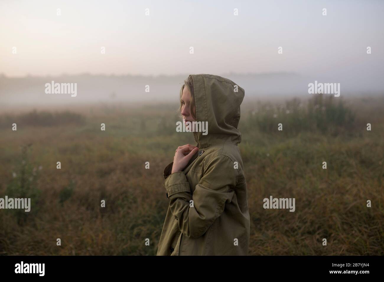 Jeune femme dans le champ au coucher du soleil Banque D'Images