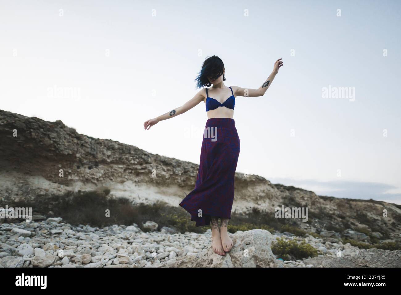 Jeune femme en soutien-gorge et jupe debout sur le rocher Banque D'Images