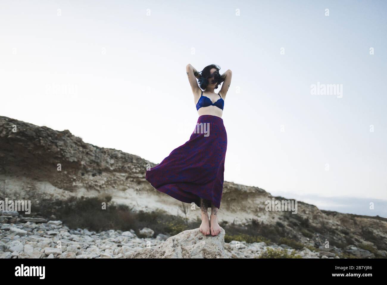 Jeune femme en soutien-gorge et jupe debout sur le rocher Banque D'Images