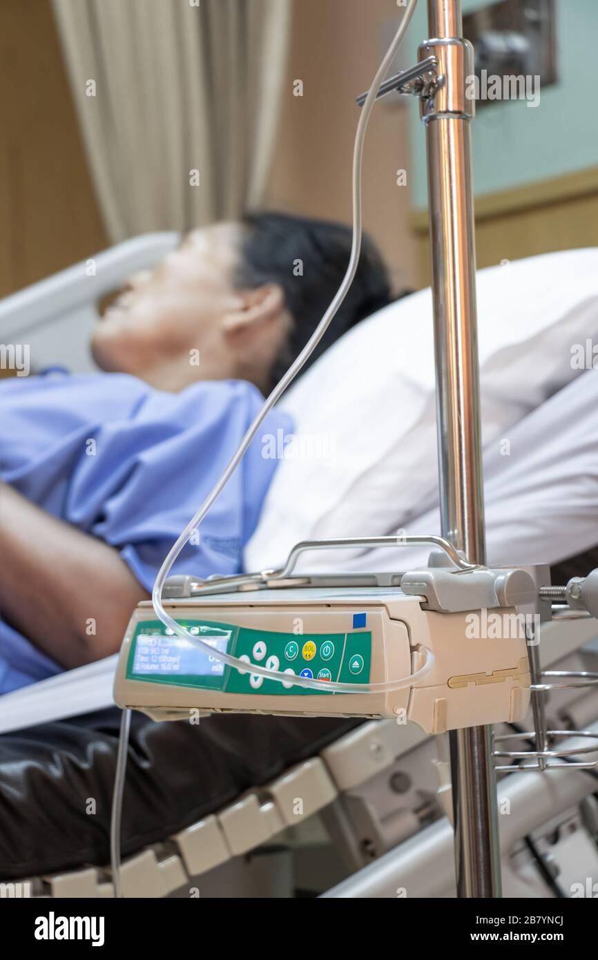 Le patient est allongé sur un lit dans un hôpital, un dispositif de perfusion automatique est installé à côté du lit. Banque D'Images
