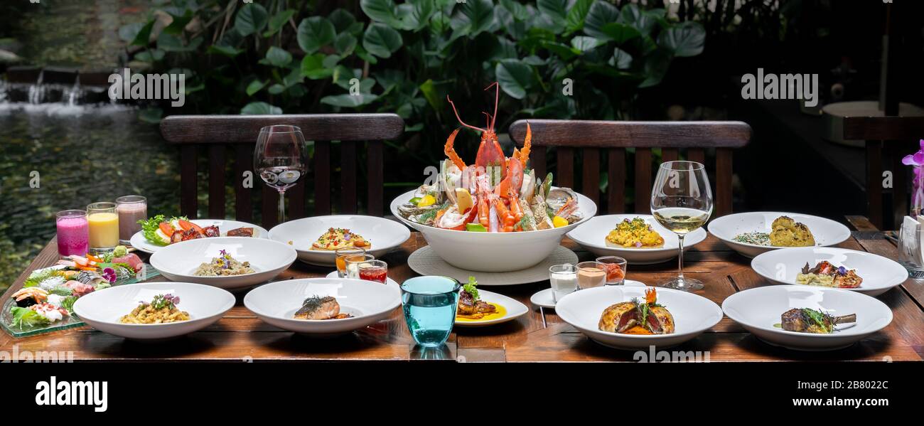 Vue latérale variété de spécialités internationales dans le jardin du restaurant de crevettes de homard steak boeuf agneau pâtes spaghetti risotto riz sushi sashimi a Banque D'Images