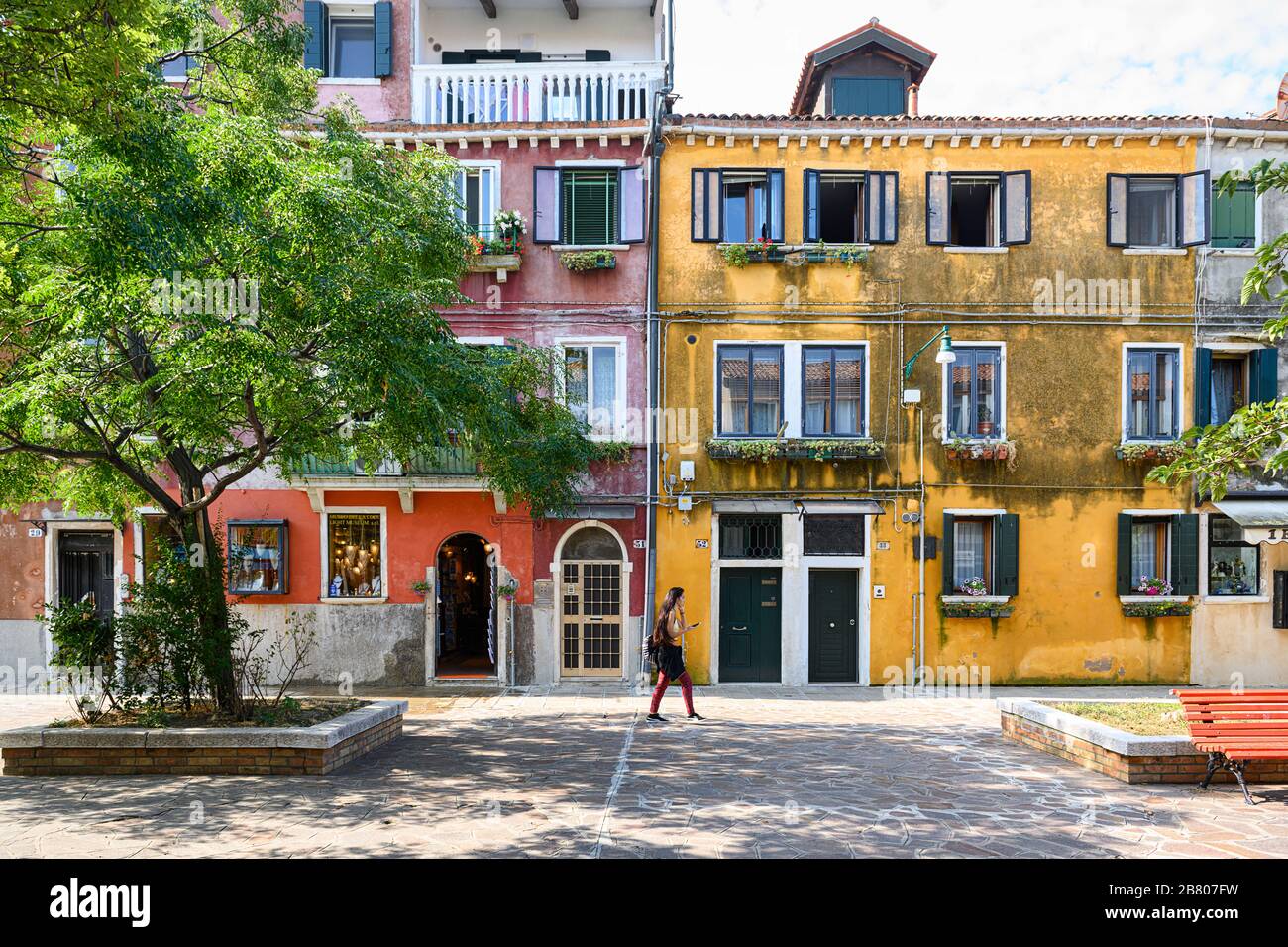 Femme marchant devant l'un des bâtiments colorés de Murano Banque D'Images