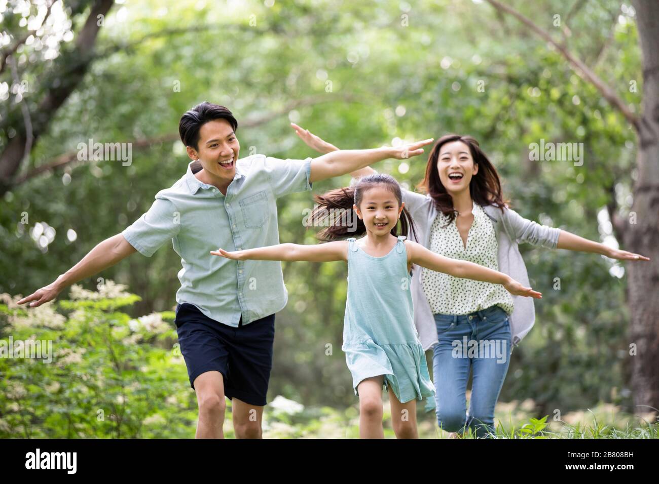 Bonne jeune famille chinoise jouant sur l'herbe Banque D'Images