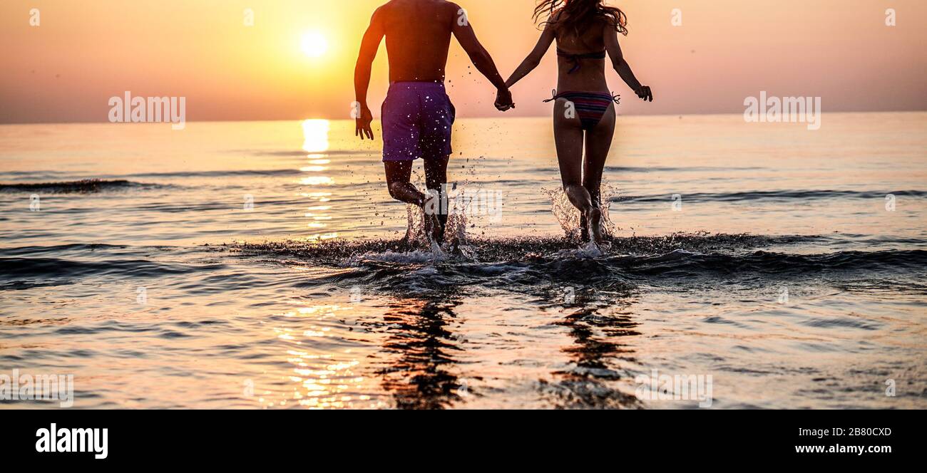 Couple D Amoureux Qui Courir Sur La Plage Dans Un Endroit Tropical Pour Des Vacances D Ete Jeunes Gens Qui S Amusent Ensemble En Plein Air Tenant Les Mains Au Coucher Du Soleil