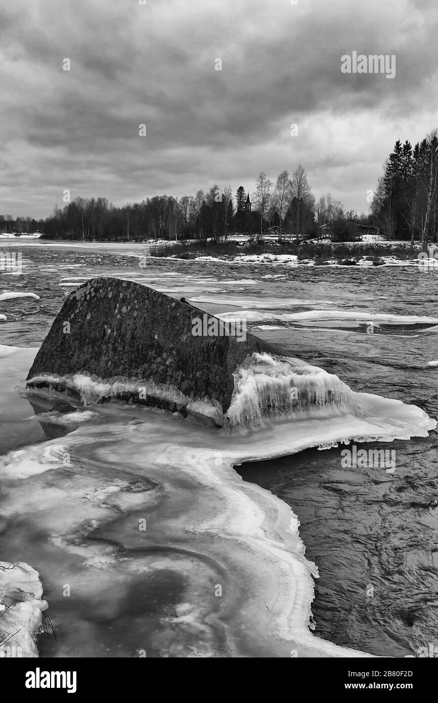 Un rocher géant est entouré de glace dans l'eau froide de la rivière dans le nord de la Finlande. Banque D'Images