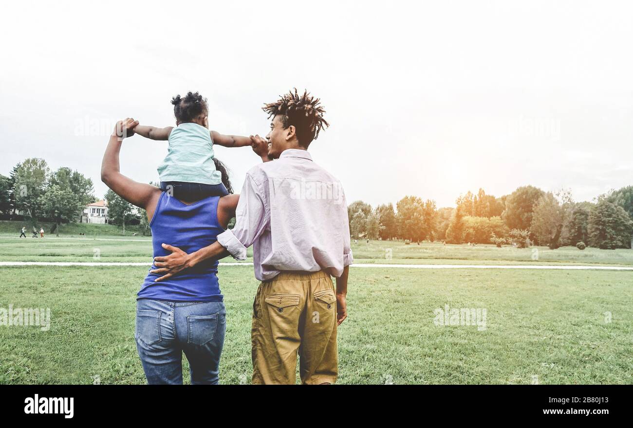 Une famille noire heureuse qui s'amuse à marcher dans le parc public en plein air - les parents et leur fille qui aiment passer du temps ensemble en un week-end - un moment d'amour tendre Banque D'Images