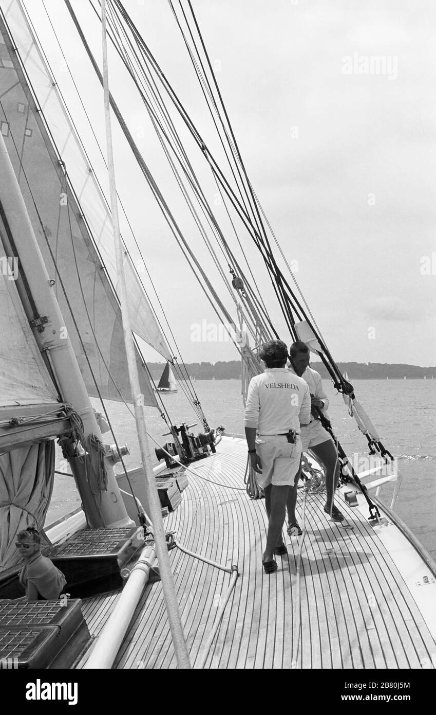 Membres d'équipage travaillant sur le pont à bord du yacht J Class 'Velsheda' après la première repose, naviguant dans le Solent, Hampshire, Angleterre, Royaume-Uni, été 1991. Archiver la photographie de film noir et blanc Banque D'Images