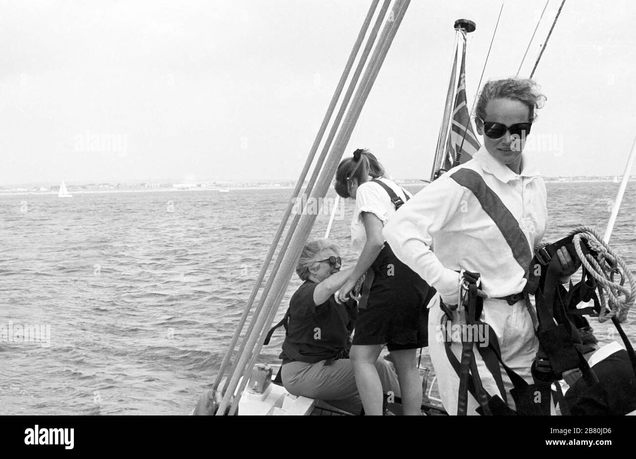 Distribution de harnais de sécurité à bord du yacht J Class 'Velsheda', naviguant dans le Solent après sa première repose, Hampshire, Angleterre, Royaume-Uni, été 1991. Archiver la photographie de film noir et blanc Banque D'Images