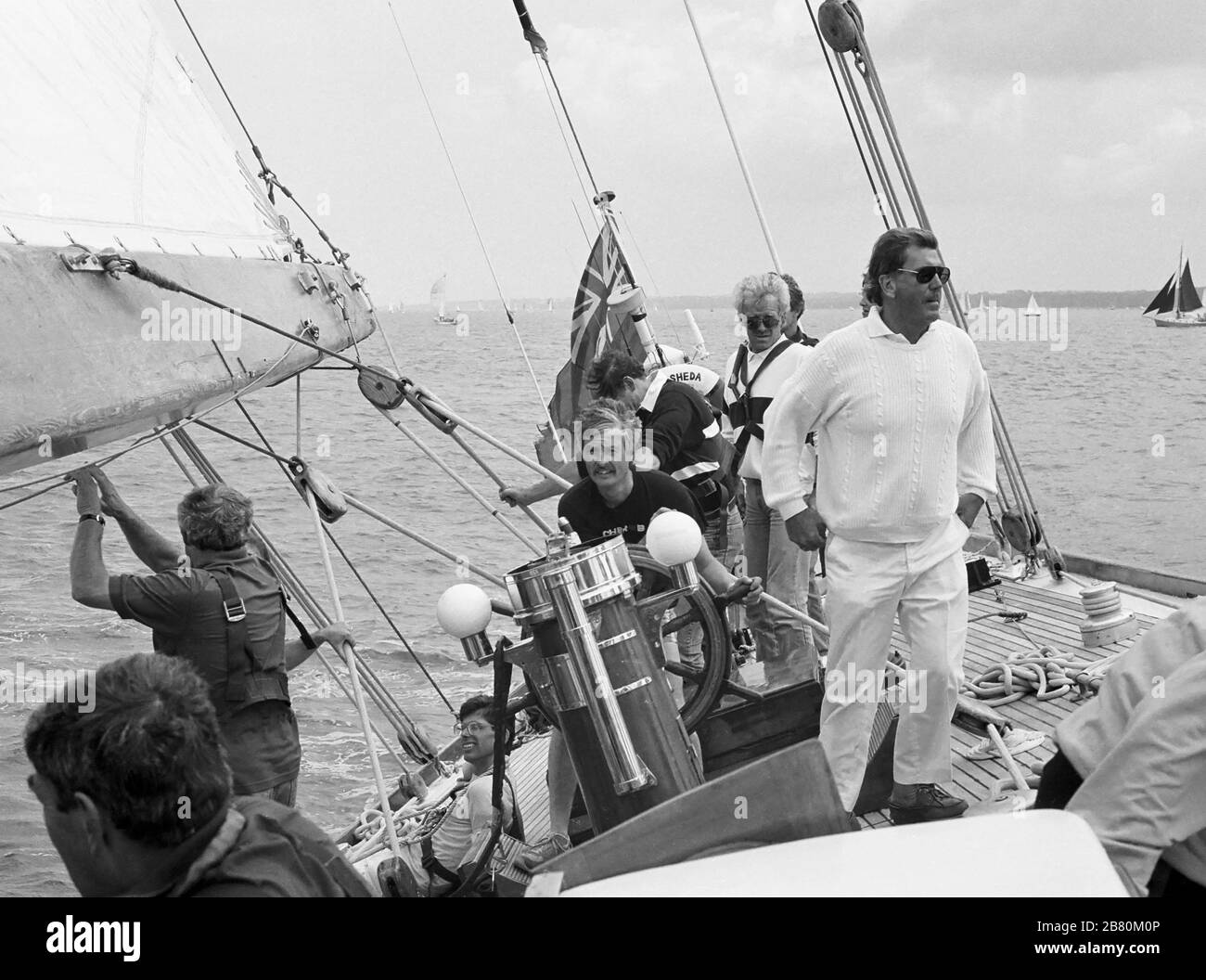 Helmsman concentrant, entouré par l'après-garde à bord du yacht de classe J 'Velsheda' (K 7): voile dans le Solent après le premier rebing, été 1991. Archiver la photographie de film noir et blanc Banque D'Images