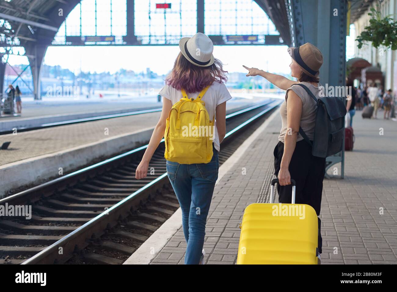 Gare, passagers avec bagages. Deux femmes voyageant avec des sacs à dos de  valise marchant le long de la plate-forme, vue arrière Photo Stock - Alamy