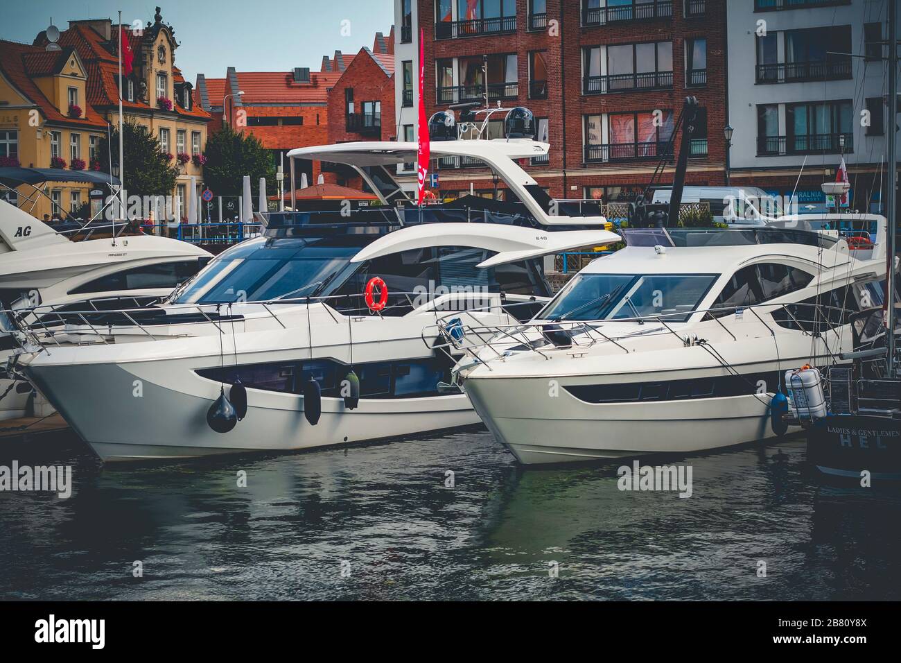Yachts modernes amarrés dans le port de plaisance de Gdansk sur la rivière New Motlawa à Gdansk, Pologne avec de vieux bâtiments en arrière-plan Banque D'Images