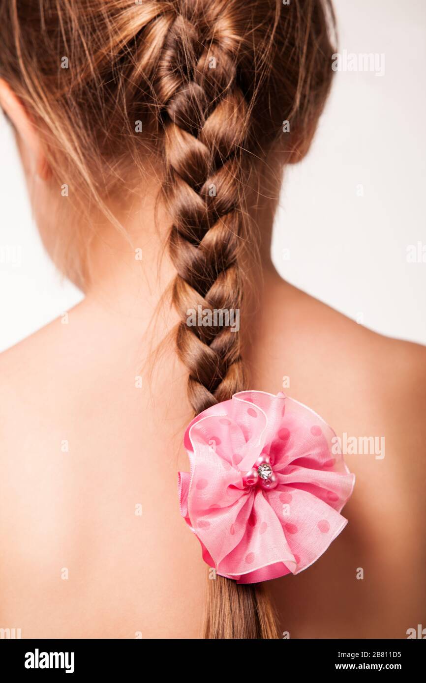 Gros Plan Sur Une Fille De Bebe Montrant Une Elegante Coiffure Tressee Avec Un Clip De Fleur Vue Arriere De L Enfant Avec Decoration Florale Dans Les Cheveux Isole Sur Qui Photo Stock