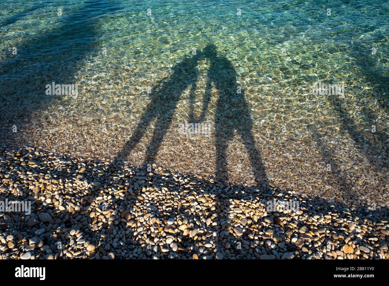 un couple affectueux sur une plage créant des ombres dans la mer Banque D'Images