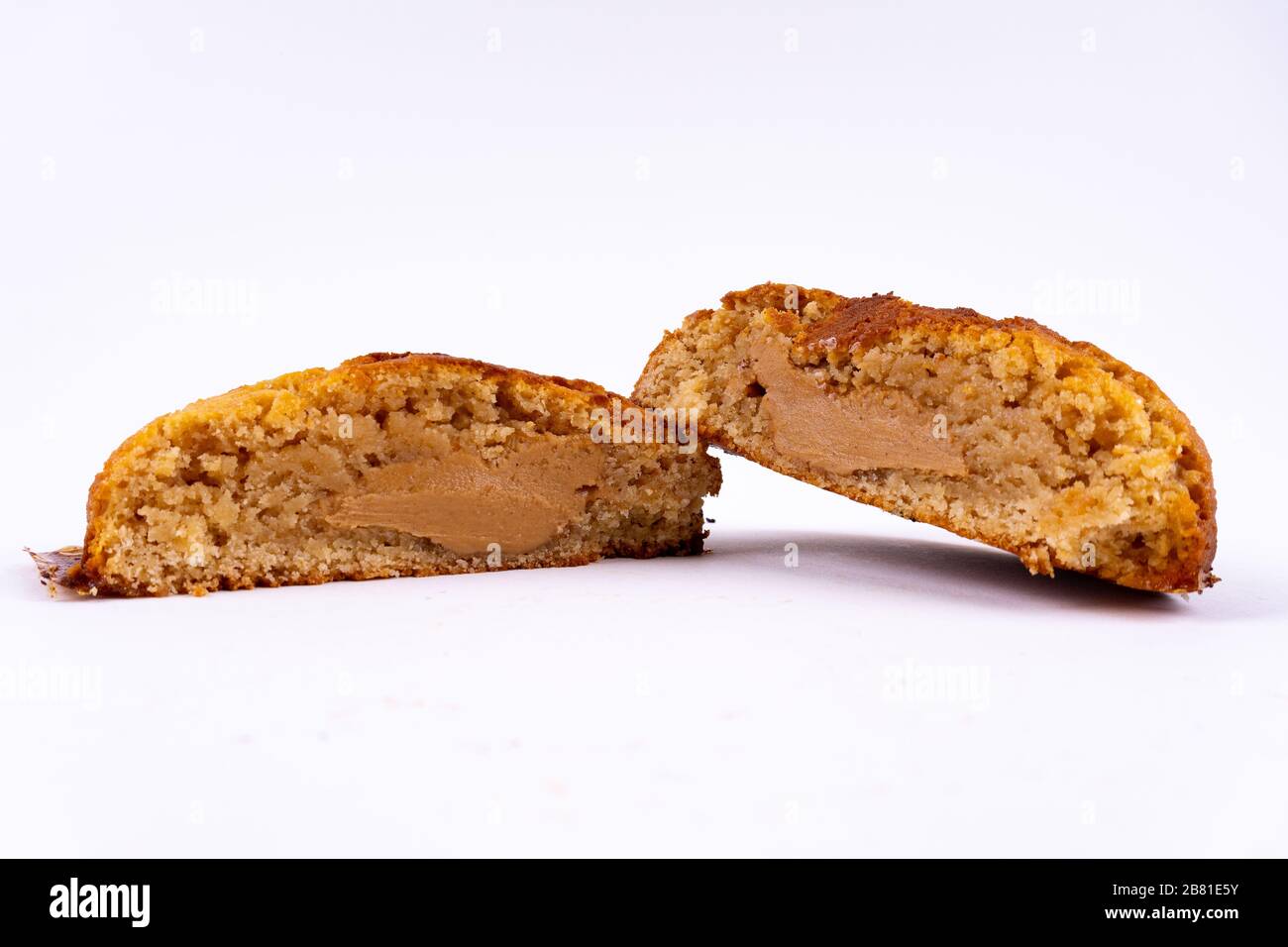 Un gâteau aux biscuits coupé avec beurre d'arachide et caramel sur fond blanc avec espace de copie - vue inclinée Banque D'Images