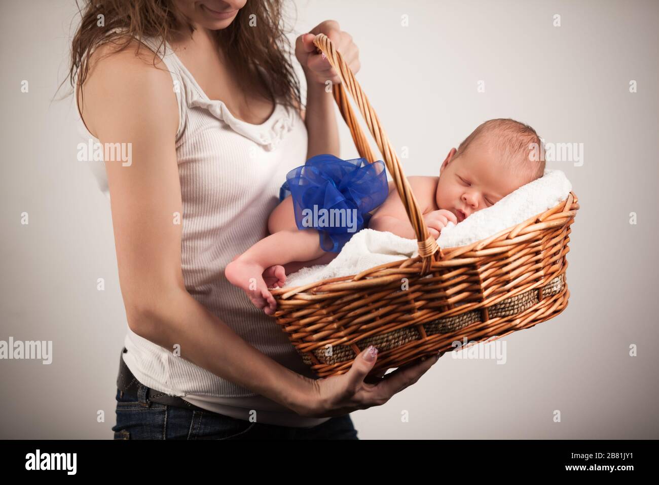 Récolte de jeune maman aimant tenant le panier cadeau avec enfant de  sommeil. Adorable bébé avec un noeud bleu sur le corps prenant la sieste  sur des draps doux. Isolé sur le