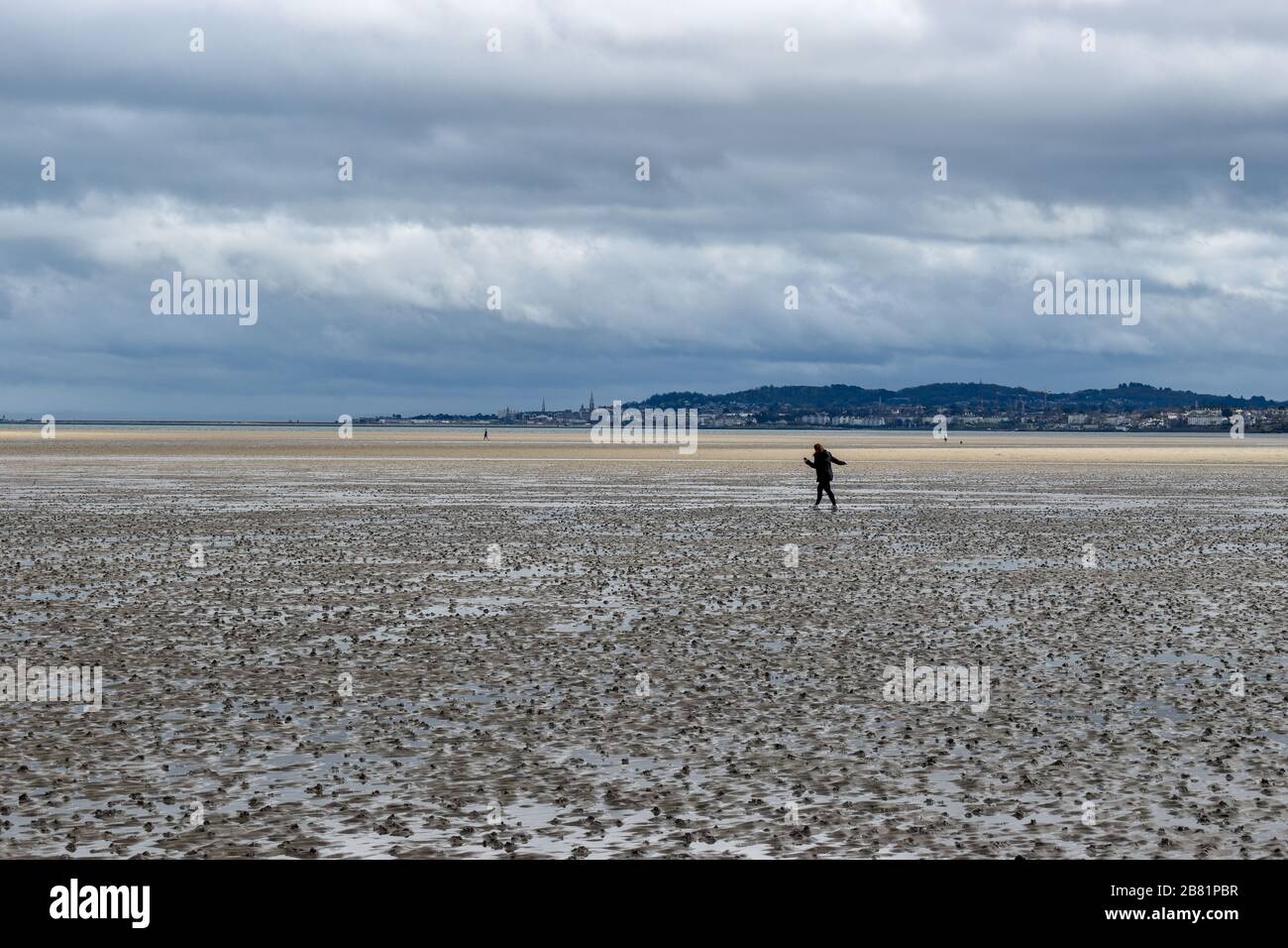 Une femme qui maintient des distances sociales marchant dehors sur la plage de Dublin, en Irlande Banque D'Images