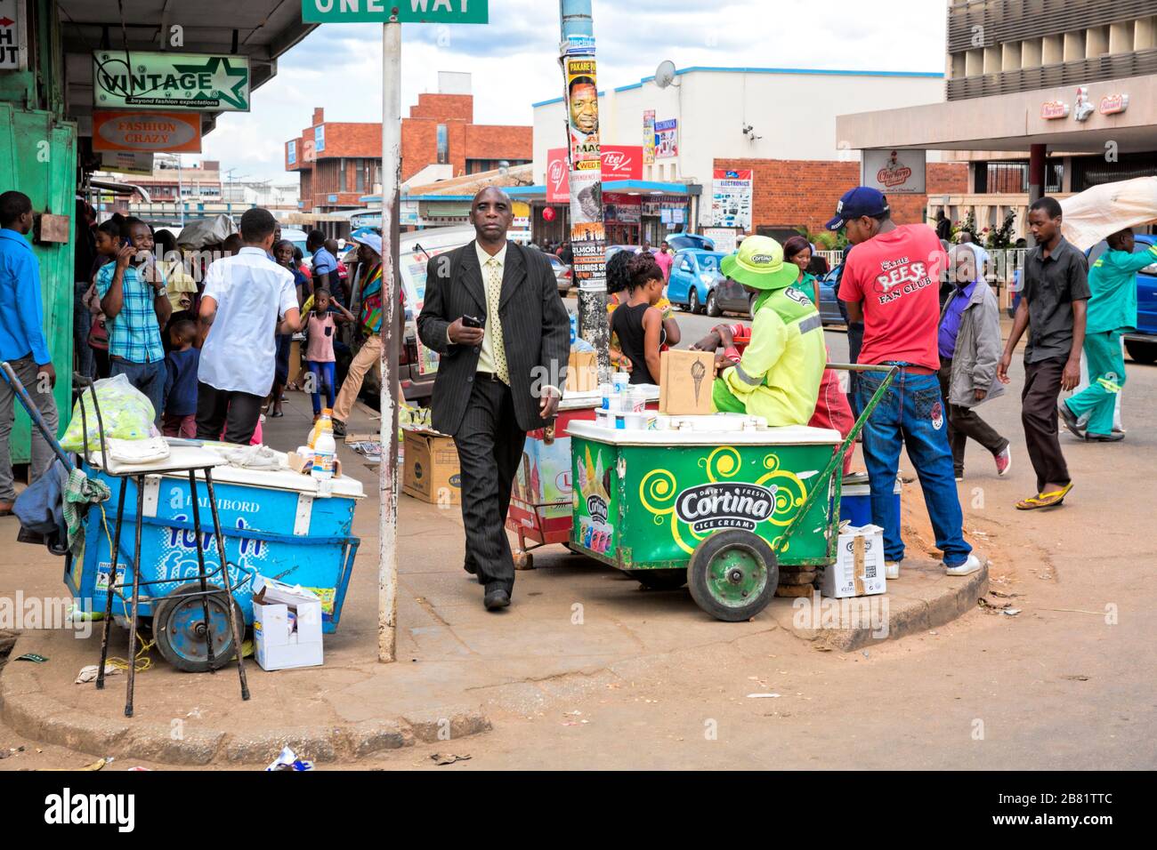 Habillé intelligemment en costume et cravate, l'homme semble hors de place lorsqu'il monte Albion Street à Chinhoyi, à travers les groupes de gens et de vendeurs de rue Banque D'Images