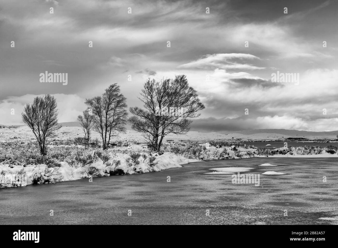 Après-midi d'hiver froid avec loch partiellement gelé et neige au Loch Ba, Rannoch Moor, Argyll et Bute, Ecosse en janvier - noir et blanc monochrome Banque D'Images