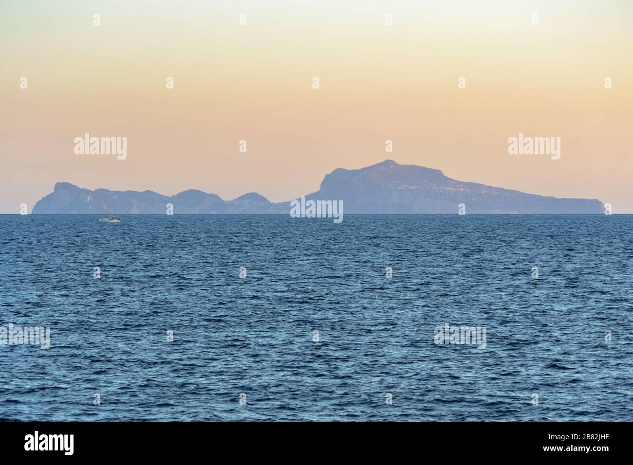 L'île de Capri sur la ligne d'horizon au-dessus du golfe de Naples vue du front de mer de la ville dans une vue sur le paysage au coucher du soleil Banque D'Images