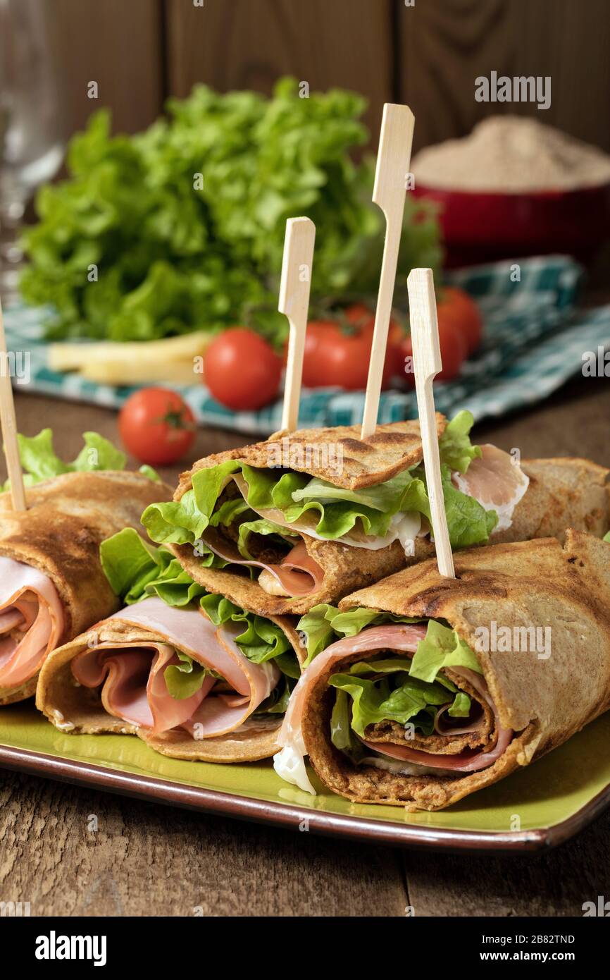 Crêpes salées de farine de mil remplies de jambon, de fromage et de salade de laitue. Banque D'Images