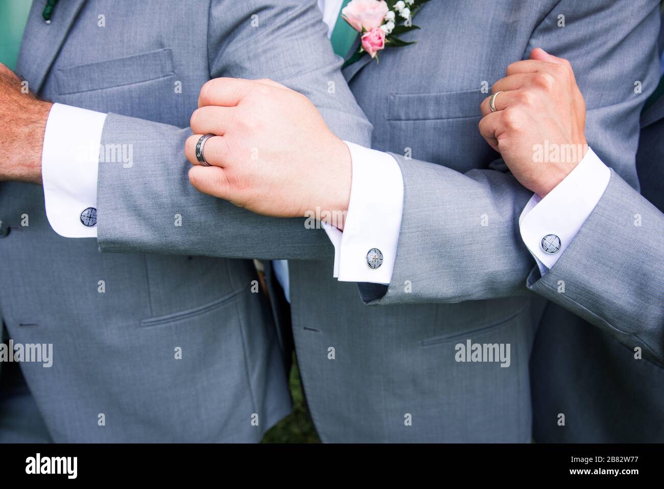 Trois groomsmen affichent des bras et des boutons de manchette Banque D'Images