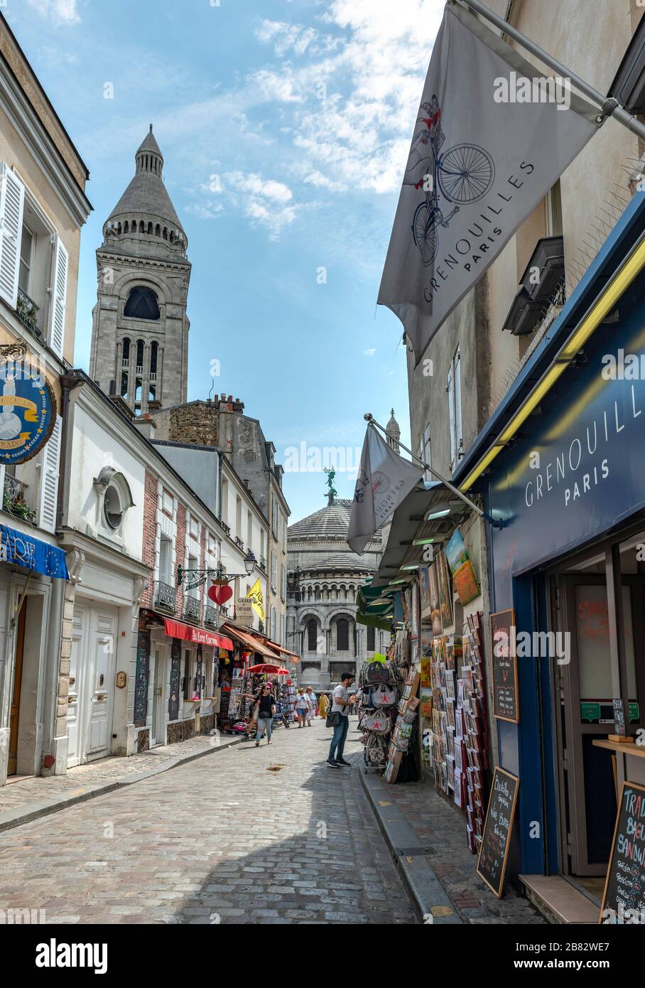 Rue avec boutiques à Montmartre surplombant le dôme de la basilique du Sacré-coeur, Paris, Ile-de-France, France Banque D'Images