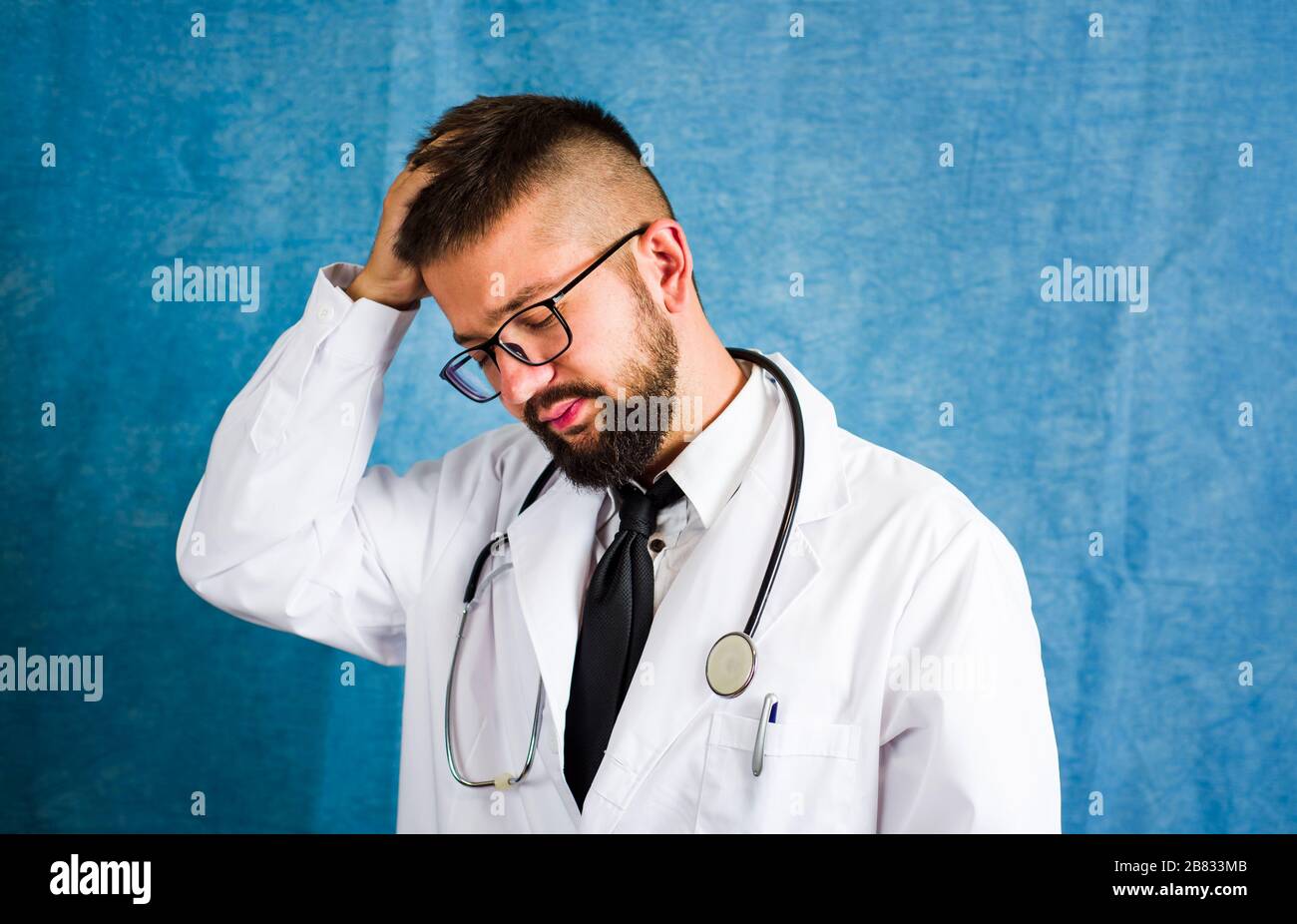 Portrait d'un jeune médecin contre fond bleu Banque D'Images