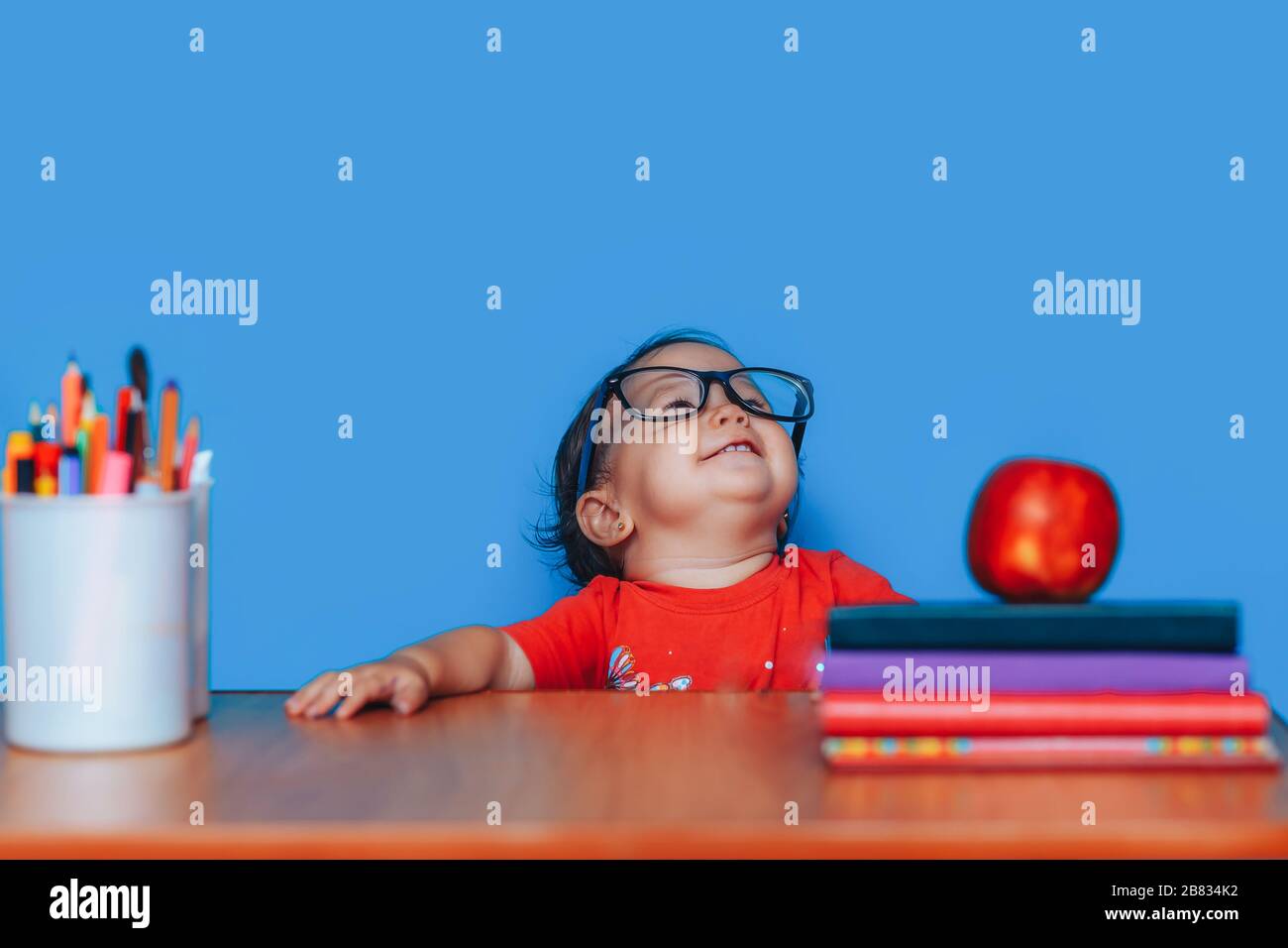 Bonne fille intelligente est assise à un bureau dans des verres. Petite fille dans des verres. Éducation précoce Banque D'Images