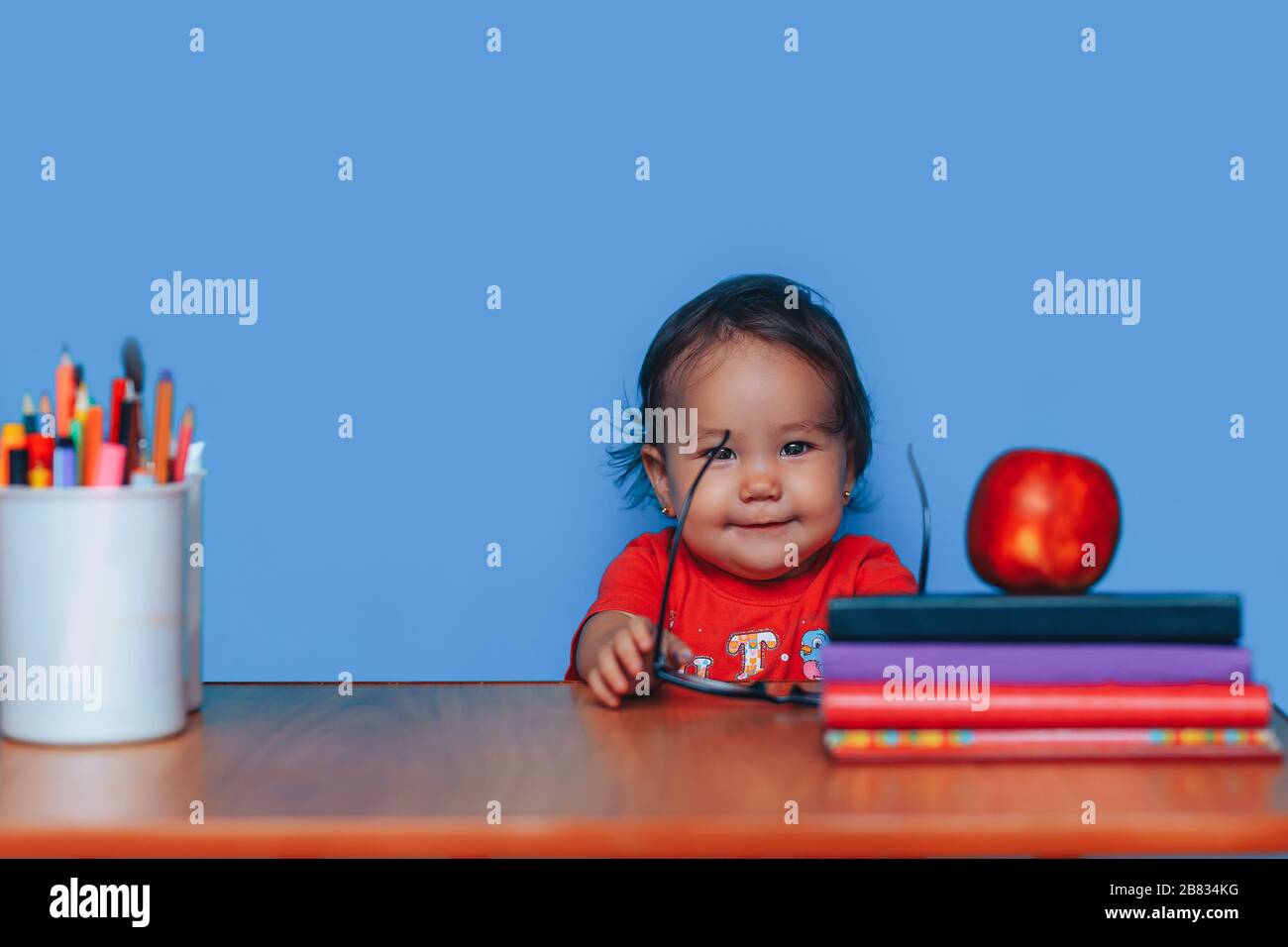 Bonne fille intelligente est assise à un bureau dans des verres. Petite fille dans des verres. Éducation précoce Banque D'Images