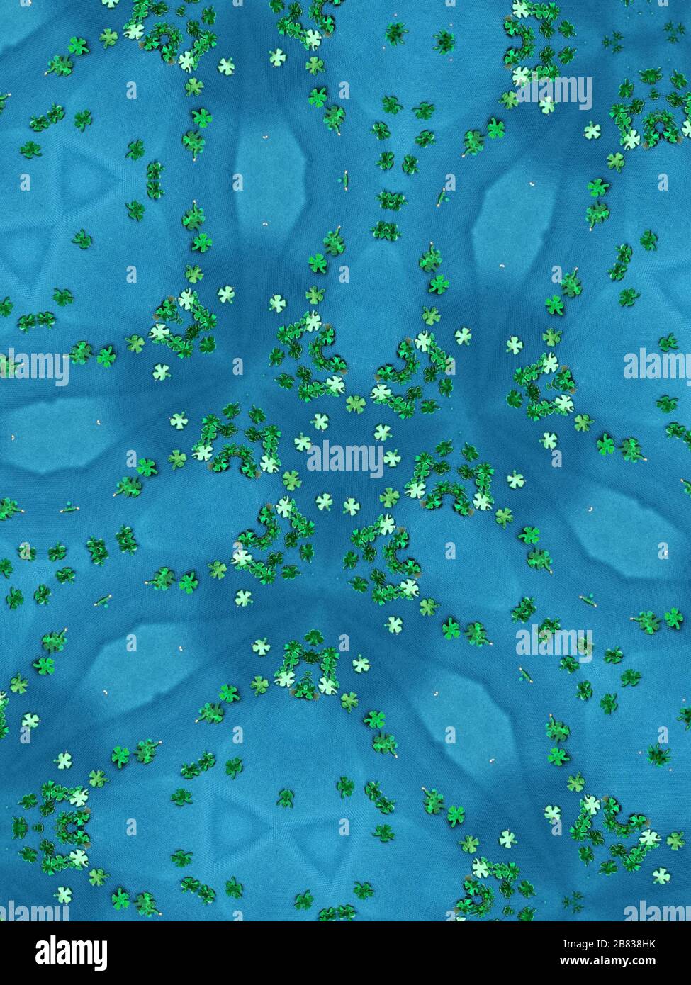 Vue réfléchissante du kaléidoscope de confettis de trèfle vert sur fond bleu ciel. Banque D'Images