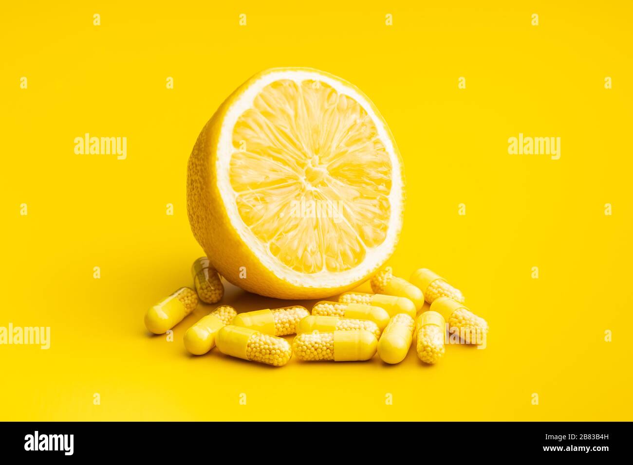 Capsules de vitamines. Pilules de vitamine C et citron jaune sur fond jaune. Banque D'Images